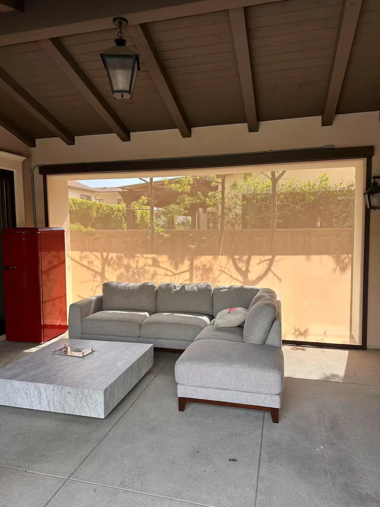 Exterior shade lowered across a covered patio seating area.