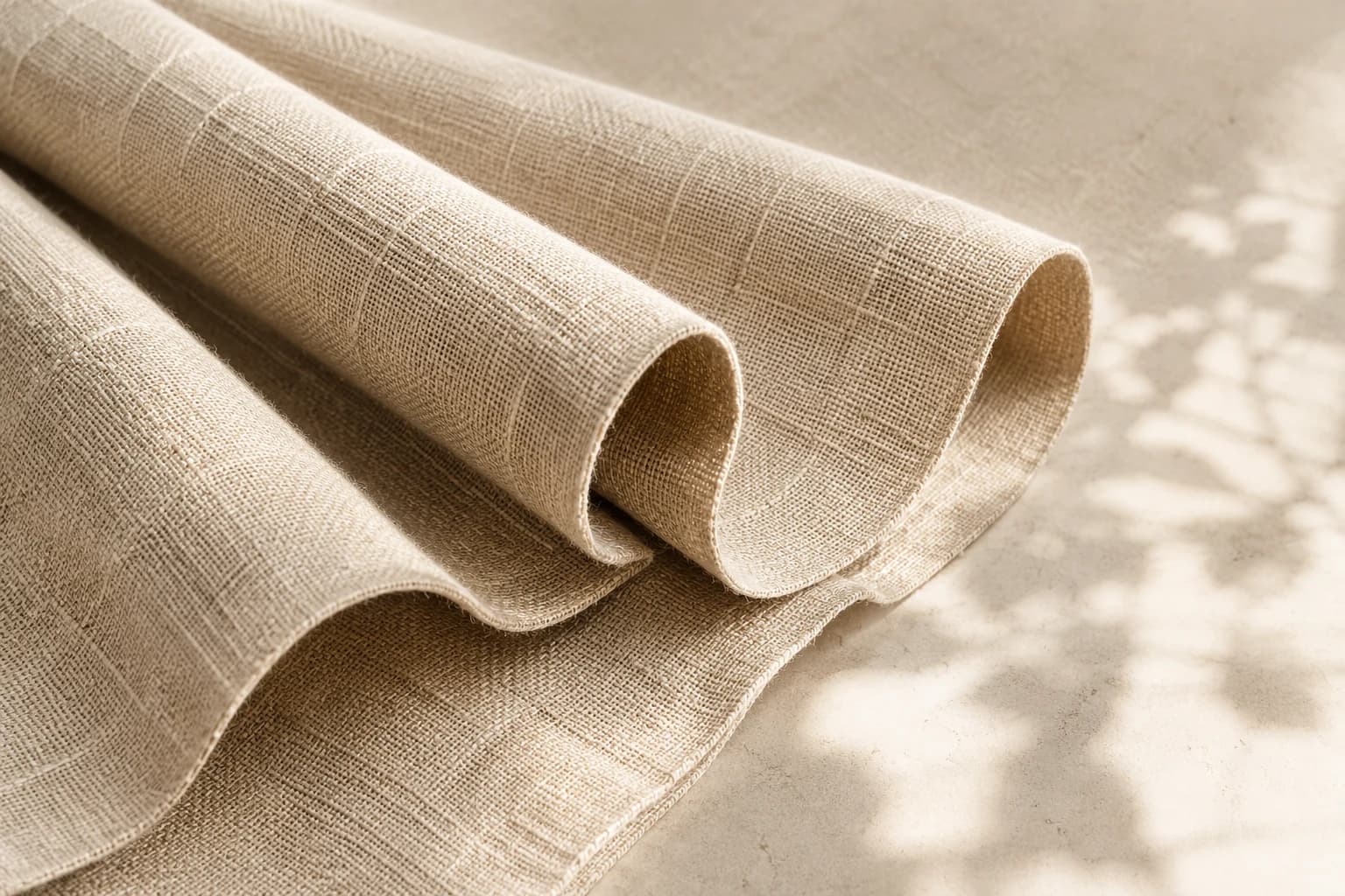 Close-up of neutral linen drapery fabric in soft daylight.