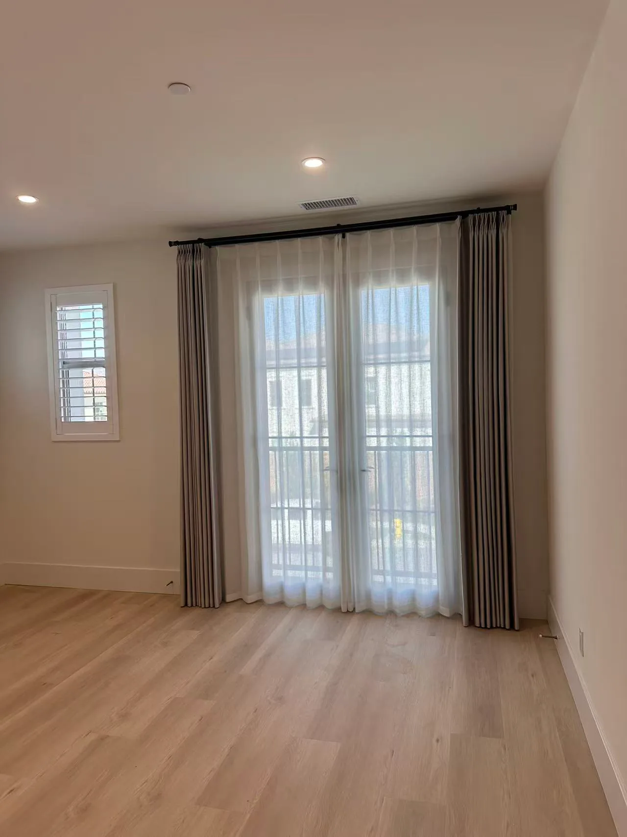 Tall drapery and sheer panels installed on a high window.