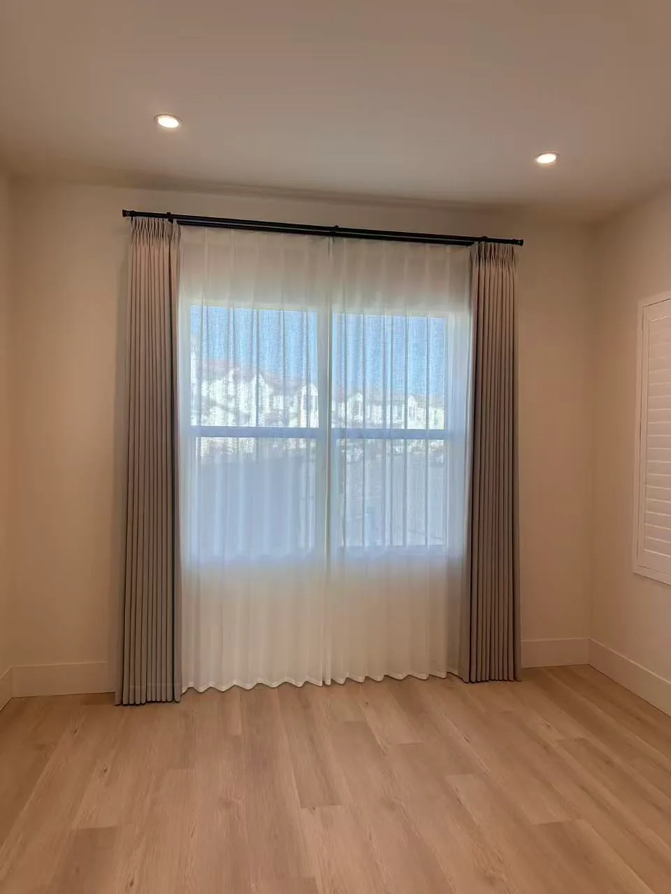 Custom drapery and sheer panels installed in an unfurnished living room.