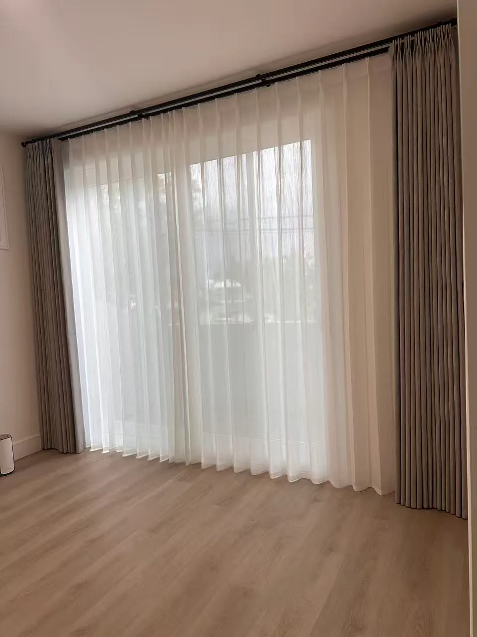 Custom drapery and sheer panels installed in a room with wood flooring.