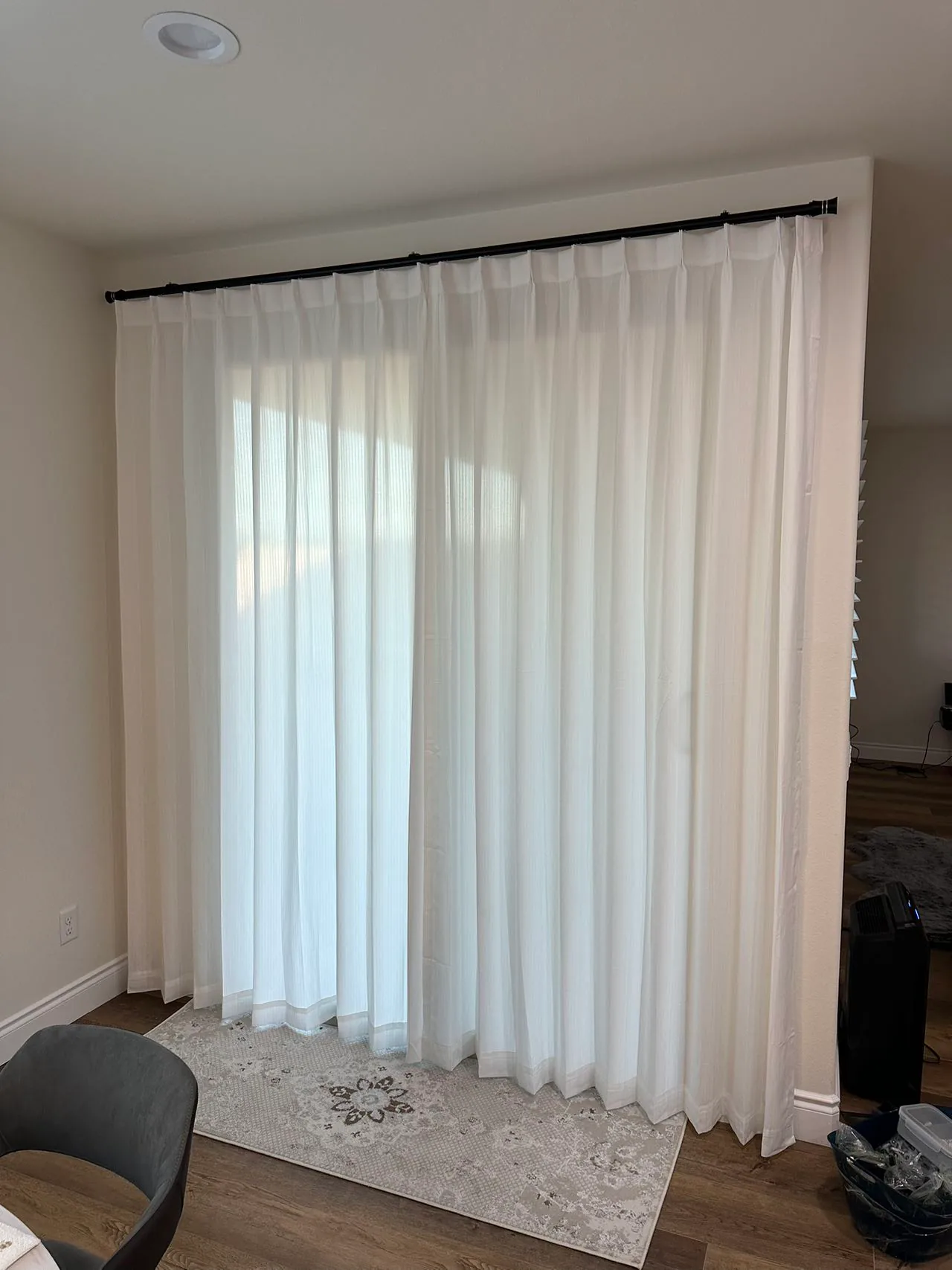 Floor-length sheer curtains installed in a bedroom seating area.