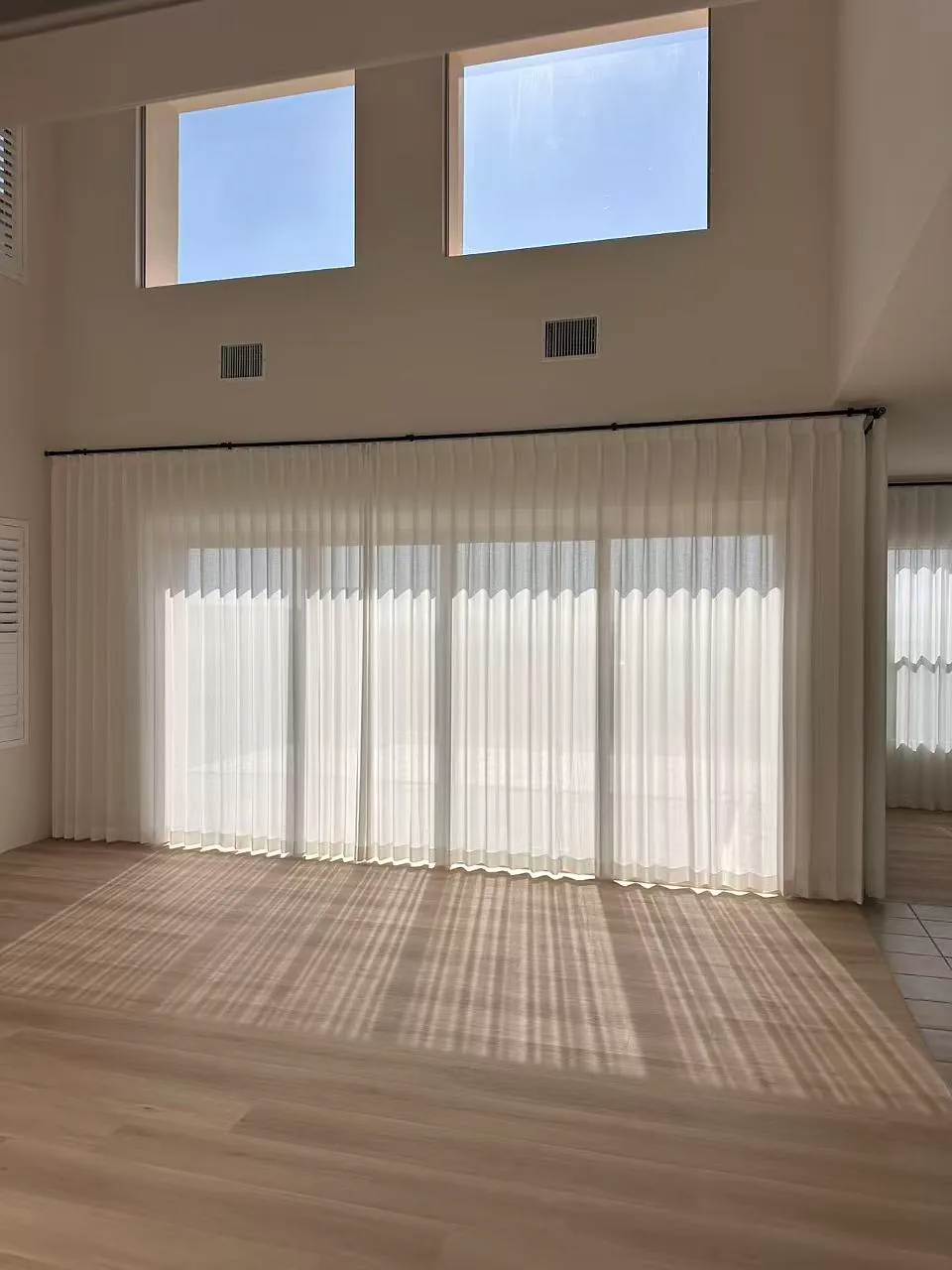 Sheer curtains installed across a wide sliding glass door opening.