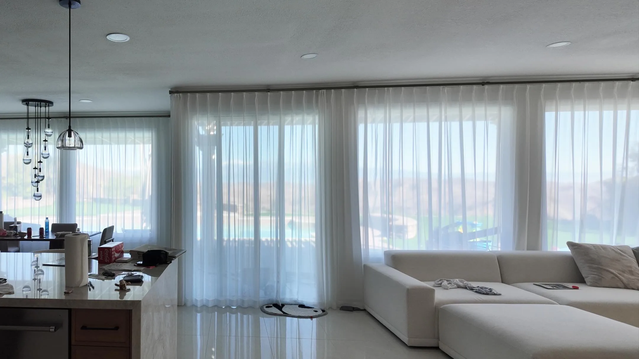 Sheer curtains filtering daylight across wide living room windows.