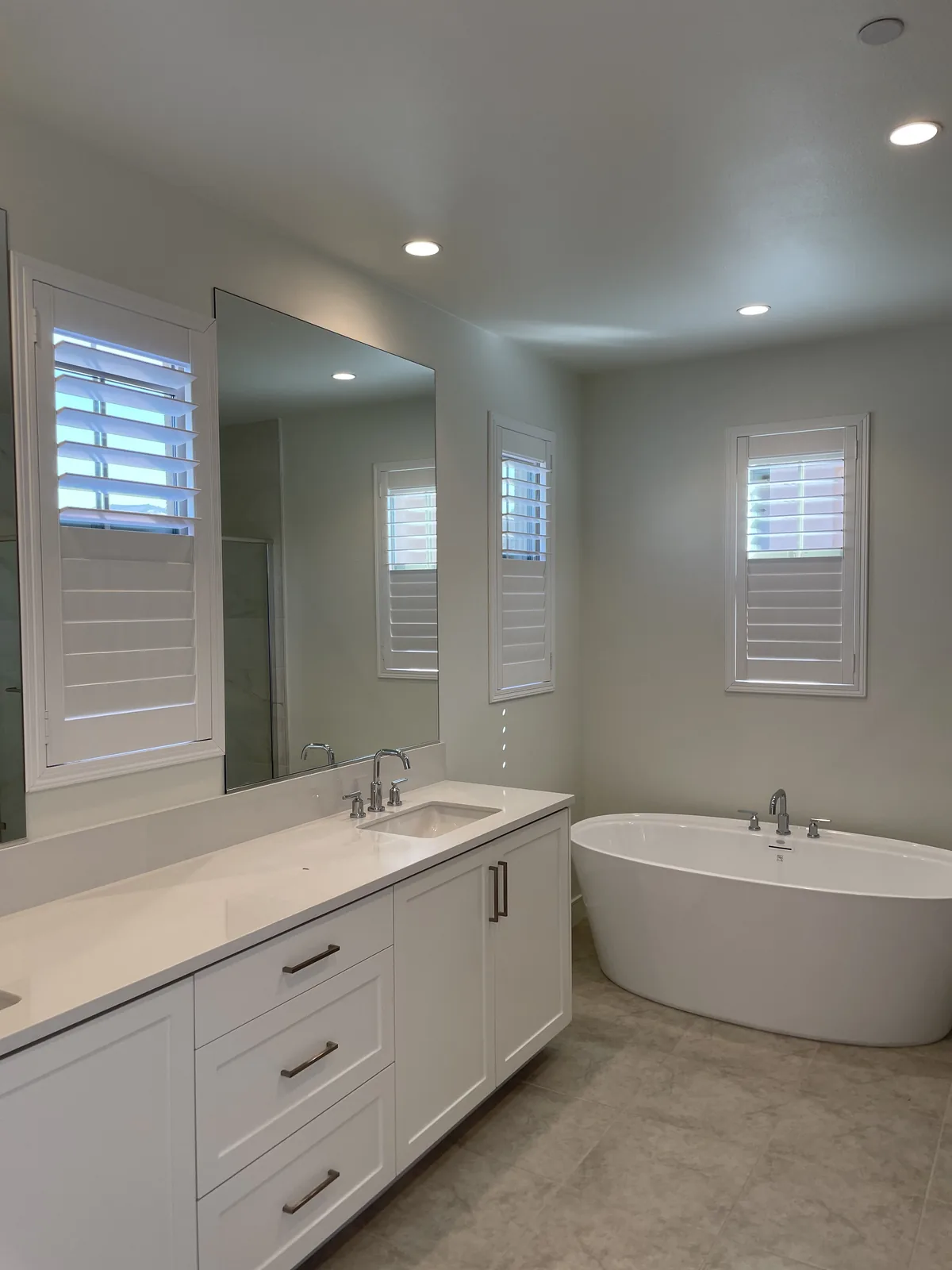 White plantation shutters around a vanity and freestanding bathtub in an Altair home in Irvine