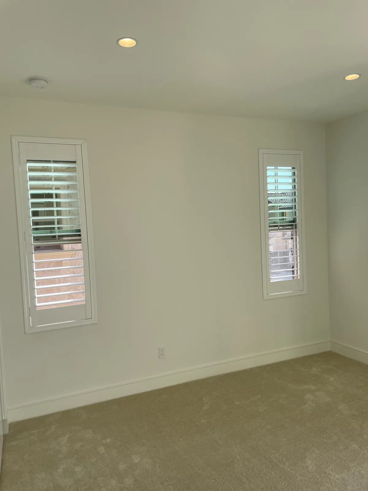 White plantation shutters on two slim bedroom windows in an Altair home