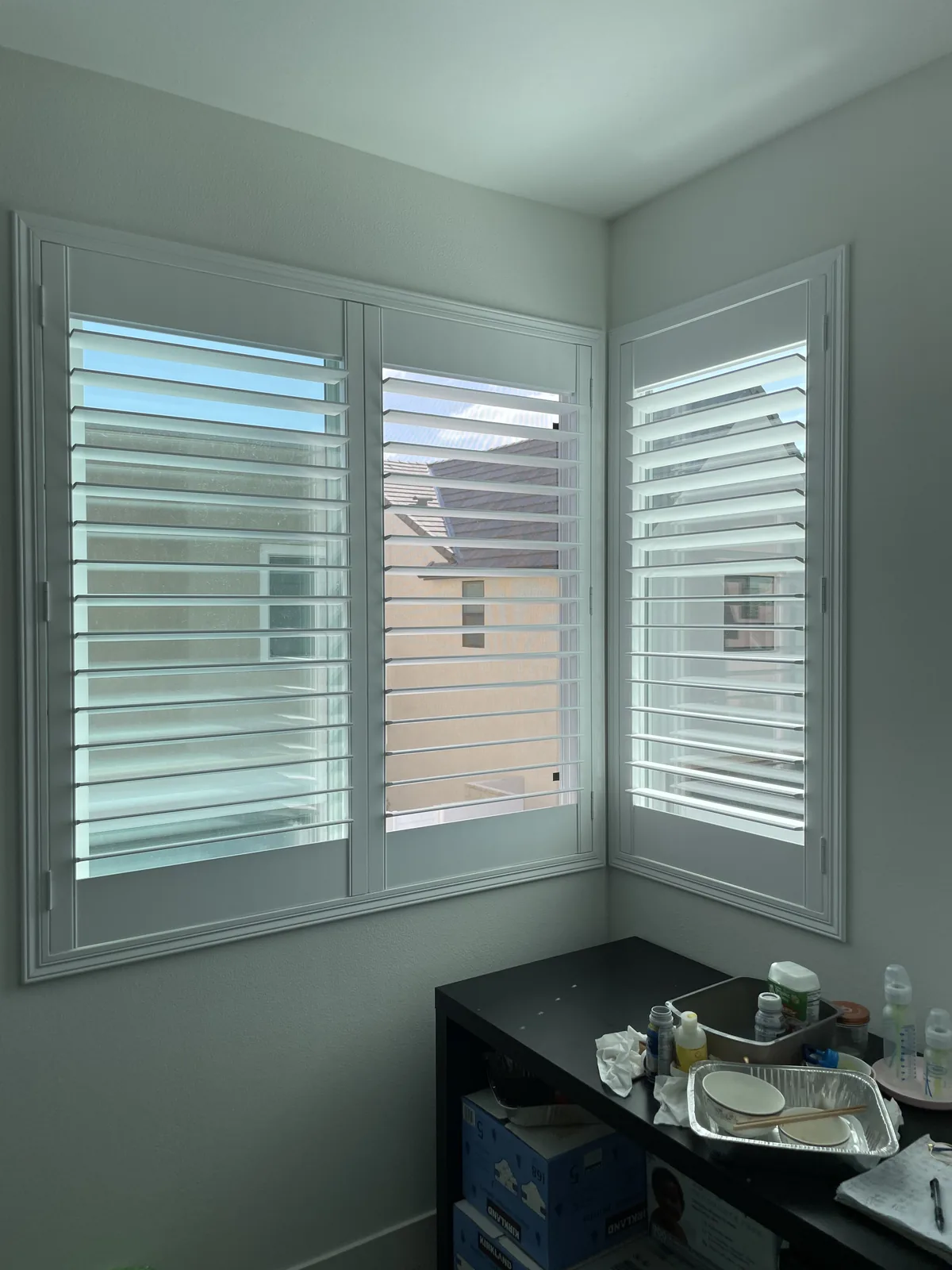 White plantation shutters on two windows meeting at a room corner
