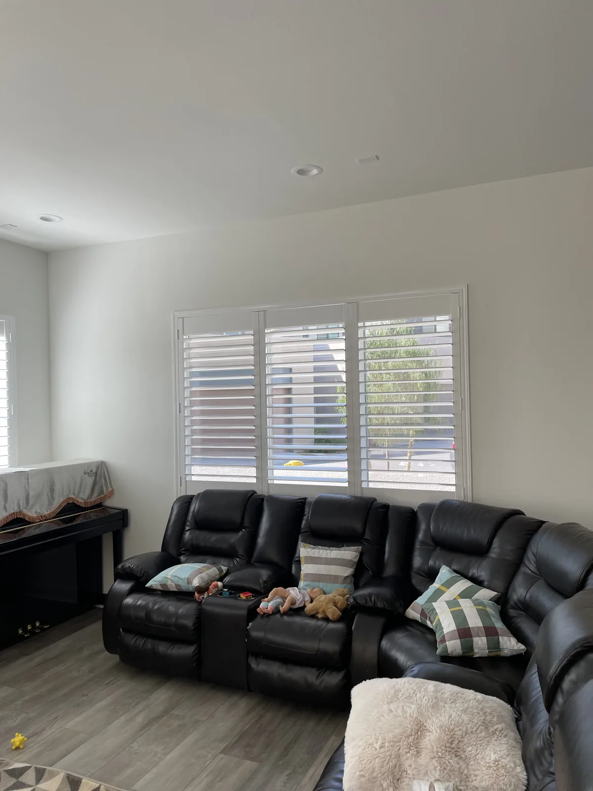 White plantation shutters across living-room windows behind a sofa in Cadence Park, Irvine