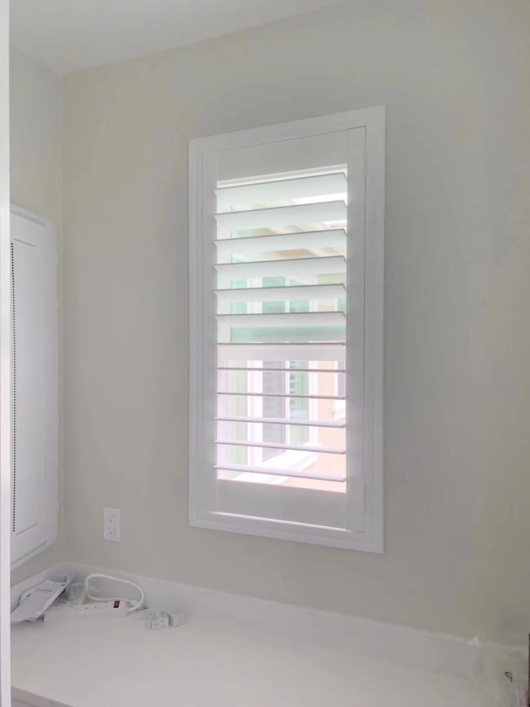 White plantation shutter on a bathroom window beside a bathtub