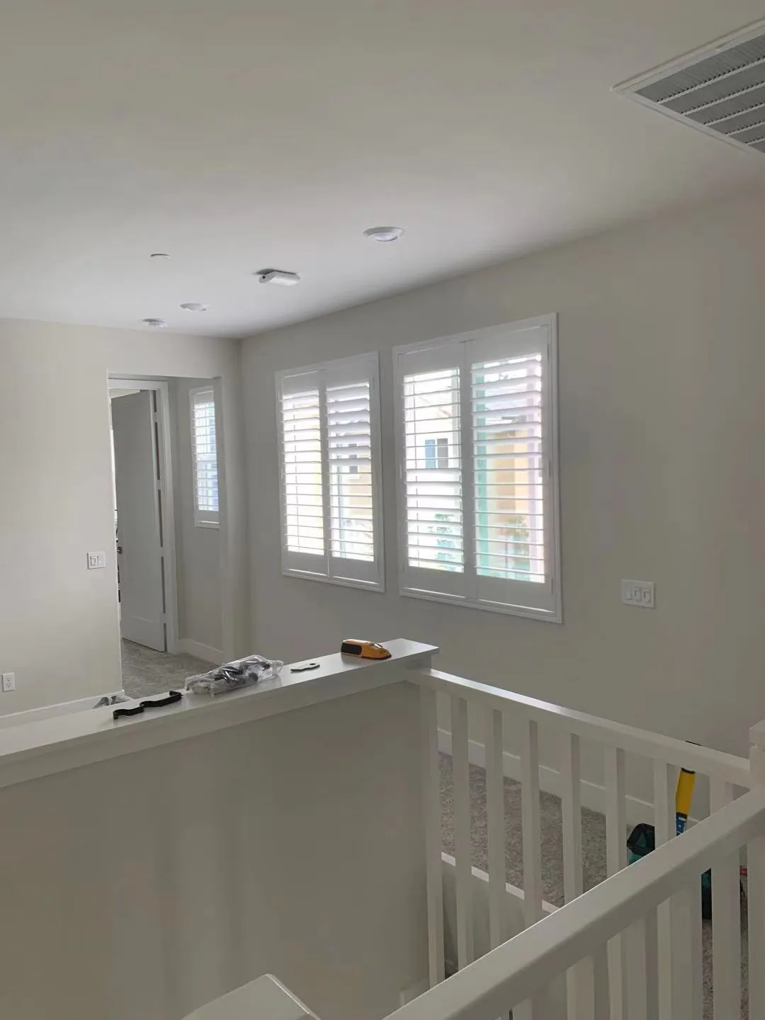 White plantation shutters on grouped windows above an upstairs railing