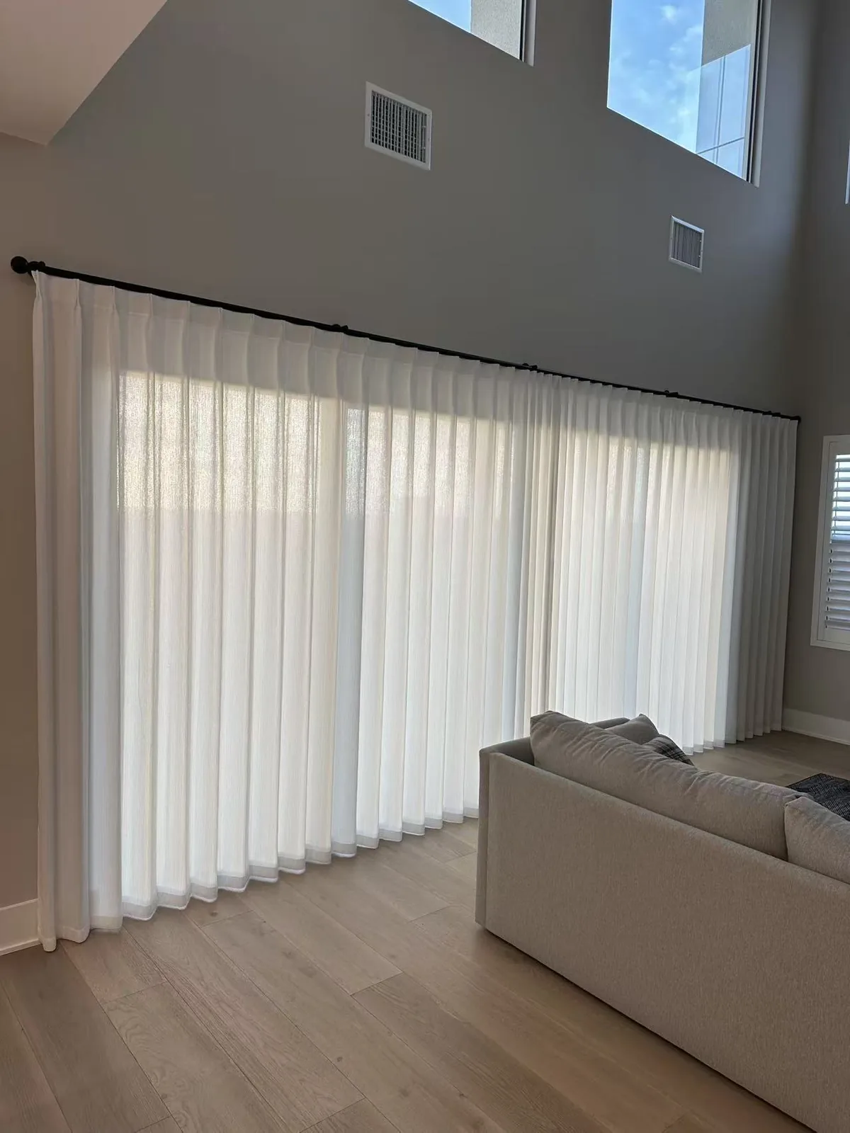 Light-colored sheer curtains across a wide opening in a high-ceiling living room in Portola Springs, Irvine