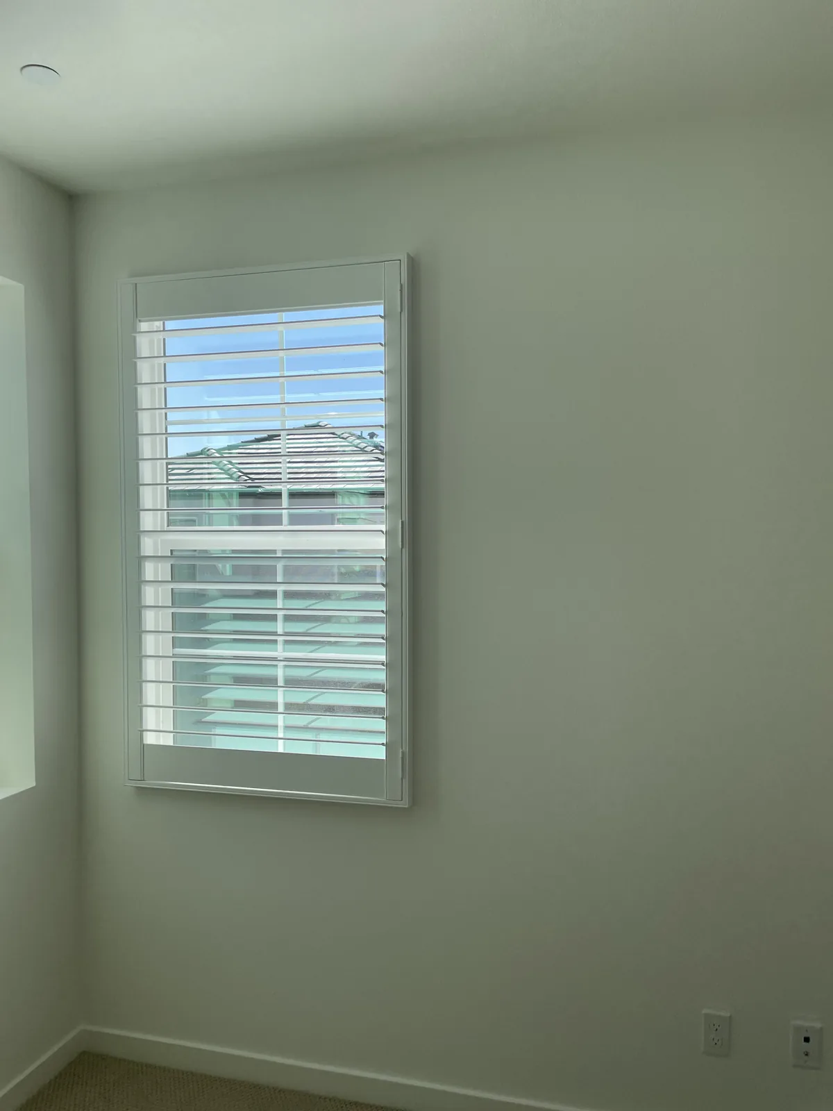 White plantation shutter fitted to a narrow rectangular window